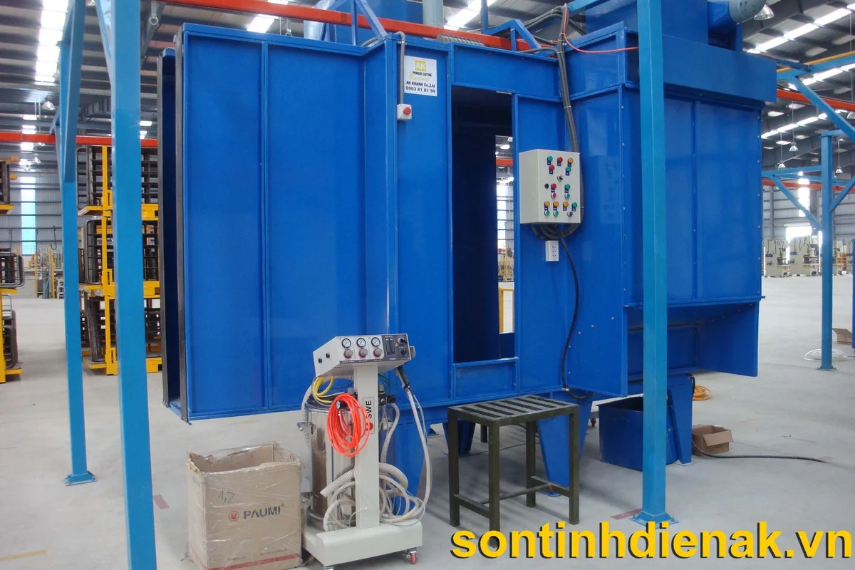 Buồng phun sơn tĩnh điện thủ công vỏ thép sơn xanh mở mặt trước, tủ điện gắn vách, bộ điều khiển súng phun có thùng cấp bột và ghế đứng đặt trước cửa buồng