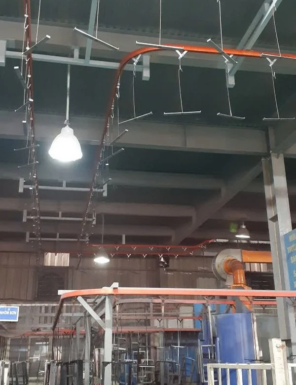 Xích tải vòng với hàng móc treo trên cao, bên dưới là khu treo và tháo hàng của dây chuyền sơn tĩnh điện